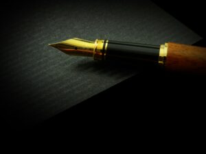 a gold pen over black paper